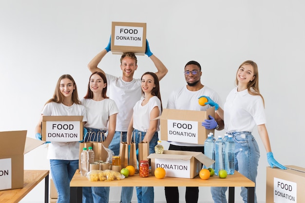 Foto gratuita voluntarios sonrientes posando junto con cajas de donación