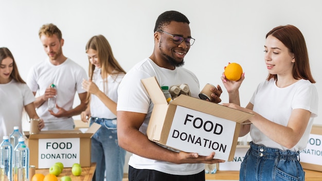 Voluntarios sonrientes preparando caja de comida para donación