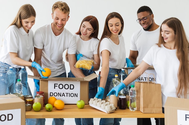 Voluntarios sonrientes preparando cajas con comida para donación