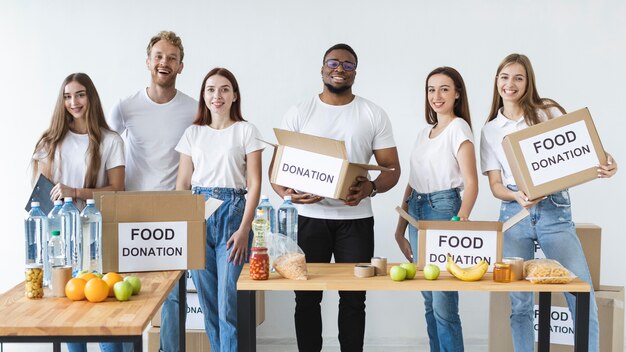 Voluntarios sonrientes preparando cajas para donación con comida