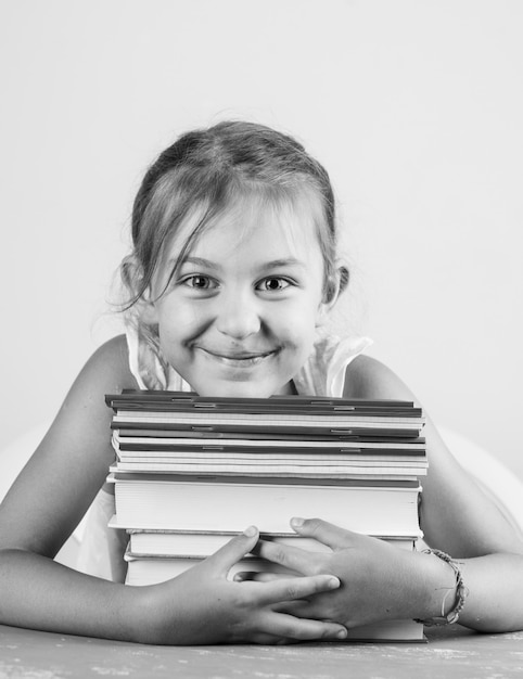 Volver al concepto de escuela en yeso y vista lateral de la pared blanca. Niña abrazando cuadernos y libros.