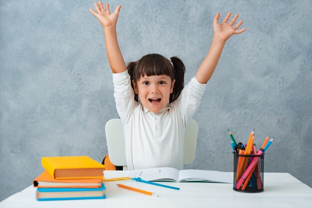 De vuelta a la escuela. Linda colegiala niño sentado en un escritorio en una habitación.