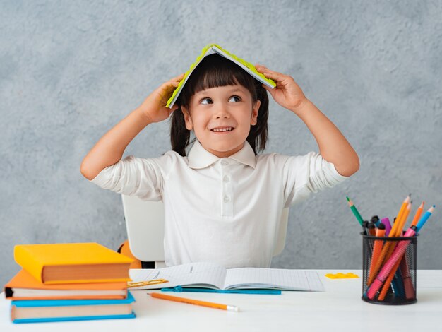 De vuelta a la escuela. Linda colegiala niño sentado en un escritorio en una habitación.