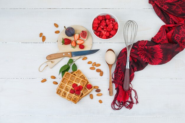 Waffles con bayas y utensilios de cocina.