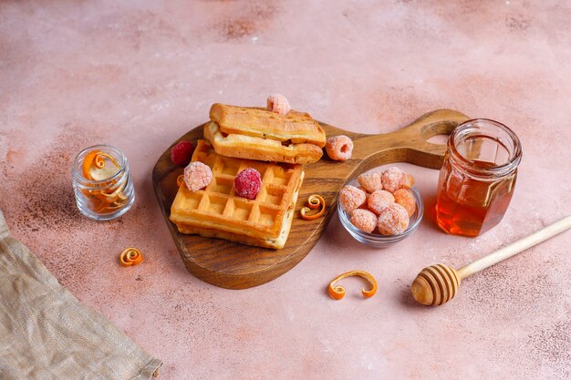 Waffles belgas tradicionales con miel y frutos rojos congelados.