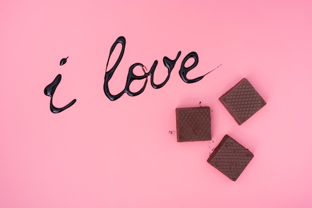 Foto gratuita waffles de chocolate sobre fondo rosa con jarabe de chocolate escrito