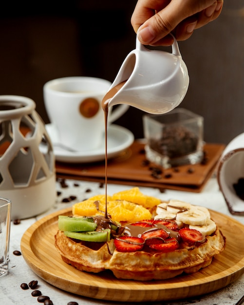 Waffles con frutas en rodajas y chocolate caliente