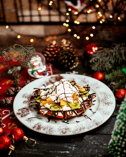 Foto gratuita waffles con frutas en rodajas y crema en la parte superior