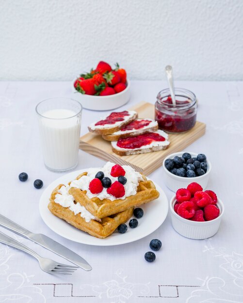 Waffles, leche y frutas de baya en la mesa