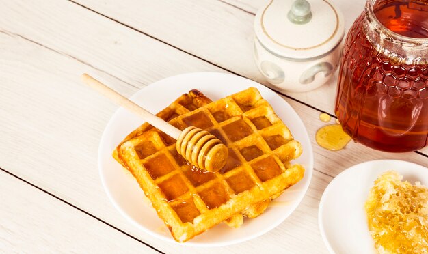 Waffles recién horneados con miel en mesa de madera