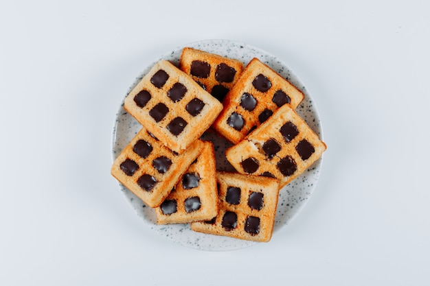 Waffles en un salvamanteles de madera sobre un fondo blanco. vista superior.