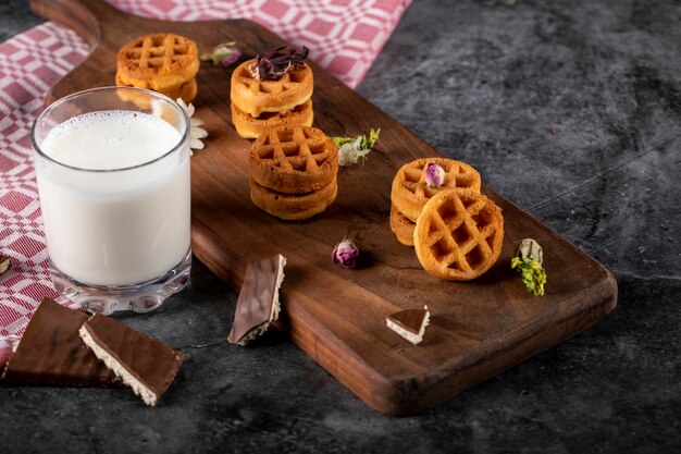 Waffles en una tabla de madera con una taza de leche.