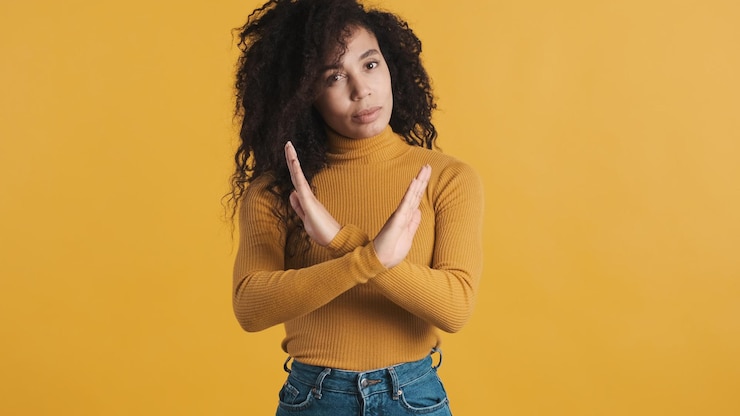 Photo Gratis wanita afrika-amerika muda dengan rambut halus yang gelap tampak percaya diri menyilangkan tangan menunjukkan tidak pada kamera di atas latar belakang penuh warna