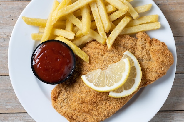 Foto gratuita wiener schnitzel con patatas fritas en la mesa de madera