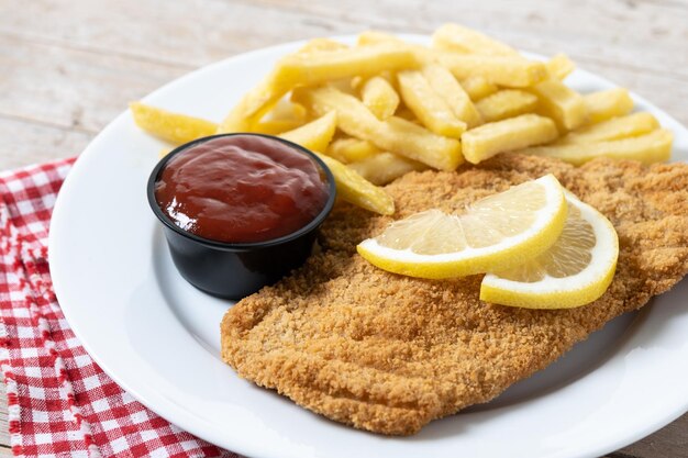 Wiener schnitzel con patatas fritas en la mesa de madera