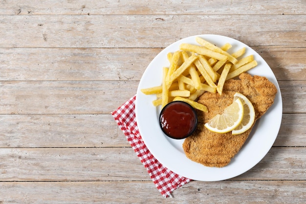 Foto gratuita wiener schnitzel con patatas fritas en la mesa de madera