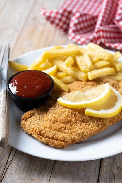 Foto gratuita wiener schnitzel con patatas fritas sobre mesa de madera