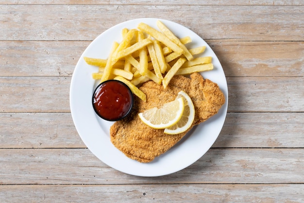 Foto gratuita wiener schnitzel con patatas fritas sobre mesa de madera