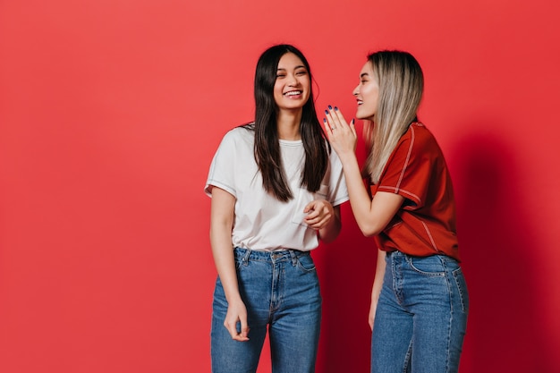 Womans alegre de buen humor charlando en la pared roja