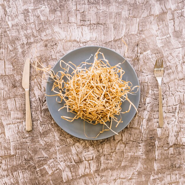 Woodshave en plato entre cuchillo de cocina y tenedor