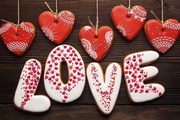 Word "love" on white cookies with hearts hanging on strings