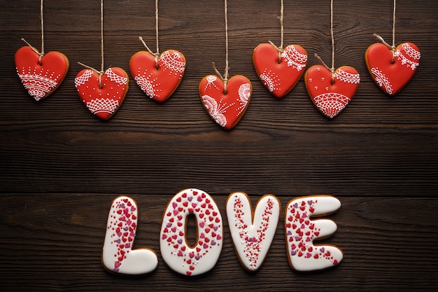 Word "love" on white cookies with hearts hanging on strings