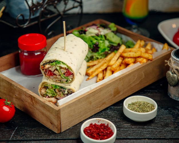 Wrap de pollo servido con papas fritas y ensalada.