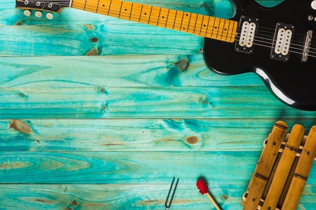 Xilófono y guitarra eléctrica clásica en mesa de madera turquesa.