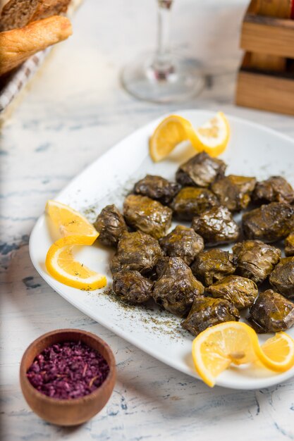 Yarpaq dolmasi, yaprak sarmasi, hojas de uva rellenas de carne y arroz, servidas con limón.