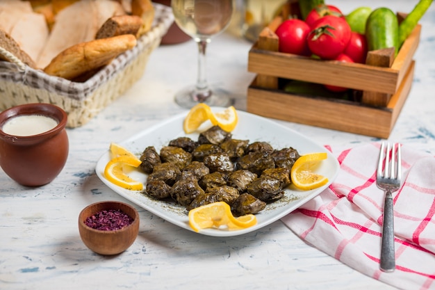 Yarpaq dolmasi, yaprak sarmasi, hojas de uva rellenas de carne y arroz, servidas con limón.