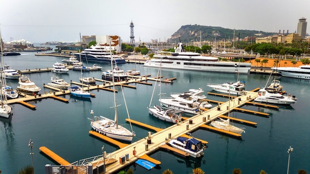 Yates amarrados en el puerto del mar Mediterráneo, edificios, vegetación en Barcelona, España
