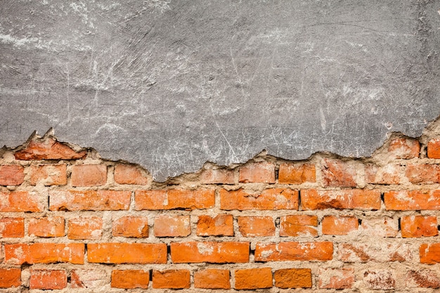 Yeso viejo y dañado en la pared de ladrillo rojo