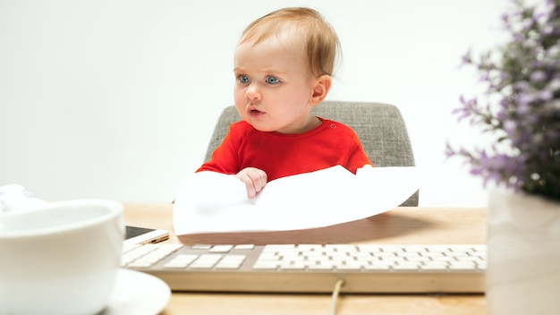 Yo soy jefe. Niño niña sentada con el teclado del ordenador o portátil moderno en estudio blanco