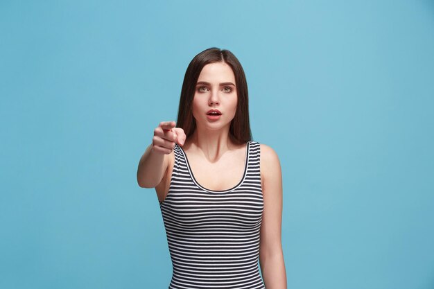 Yo te elijo y orden. La mujer sorprendida te señala, te quiere, retrato de primer plano de media longitud sobre fondo azul de estudio. Las emociones humanas, el concepto de expresión facial. Vista frontal. Colores de moda