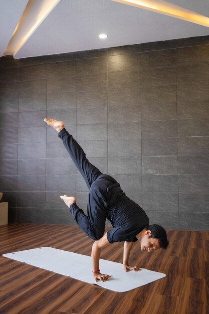 Yogi haciendo mano avanzada soporte de yoga plantean en el gimnasio