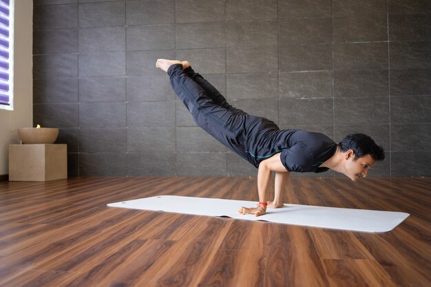 Yogui indio haciendo una posición avanzada de yoga en el gimnasio