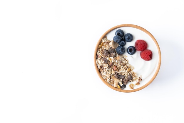 Yogur con bayas y muesli para desayunar en un recipiente aislado de fondo blanco