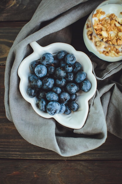 Foto gratuita yogur con granola y arándanos frescos en recipiente de vidrio sobre fondo de madera vieja efecto vintage