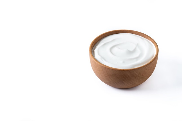 Yogur griego en cuenco de madera aislado sobre fondo blanco.