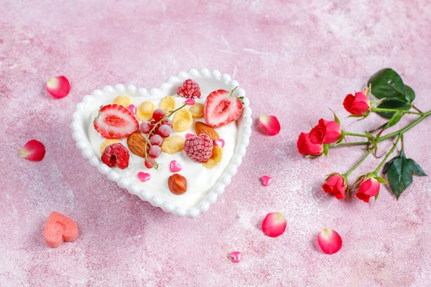 Yogur con hojuelas de maíz y frutos rojos en un recipiente con forma de corazón.