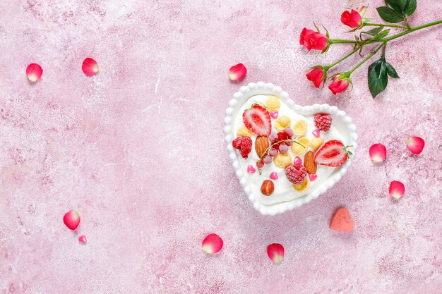 Yogur con hojuelas de maíz y frutos rojos en un recipiente con forma de corazón.