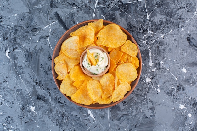 Yogur y patatas fritas crujientes en placa, sobre la superficie de mármol