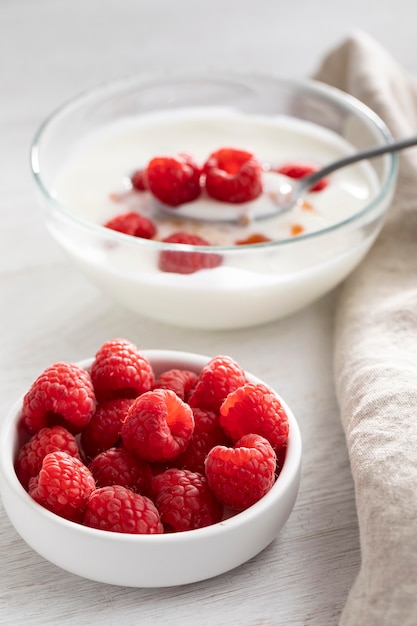 Yogur con tazón de frambuesas alto ángulo