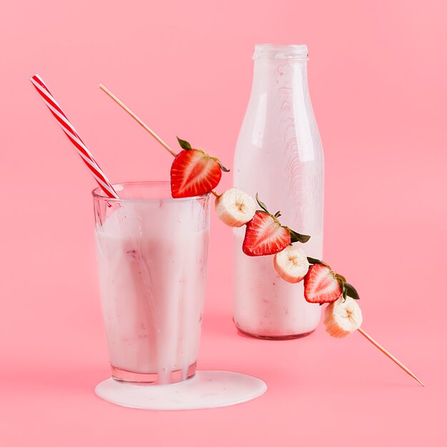 Yogurt rosa en botella y vaso con bayas.
