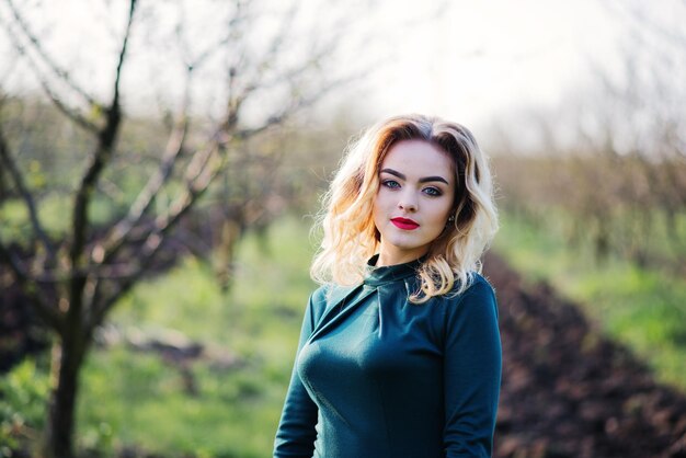 Yong elegancia chica rubia en vestido verde en el jardín en primavera