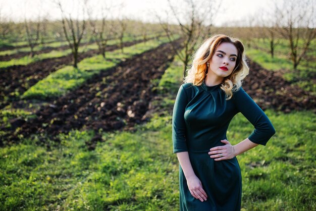 Yong elegancia chica rubia en vestido verde en el jardín en primavera