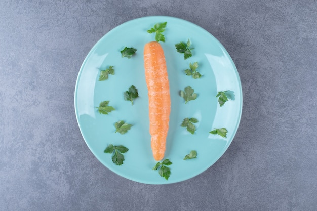 Foto gratuita una zanahoria en el plato con verduras, sobre la superficie de mármol.