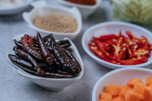 Zanahorias cortadas en cubitos, chiles secos, arroz tostado y pasta de chiles sobre un piso de cemento.