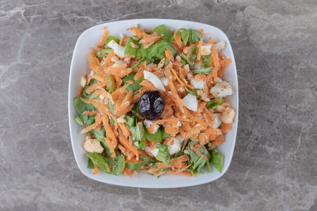 Zanahorias cortadas en cubitos y ensalada de verduras en un tazón blanco.