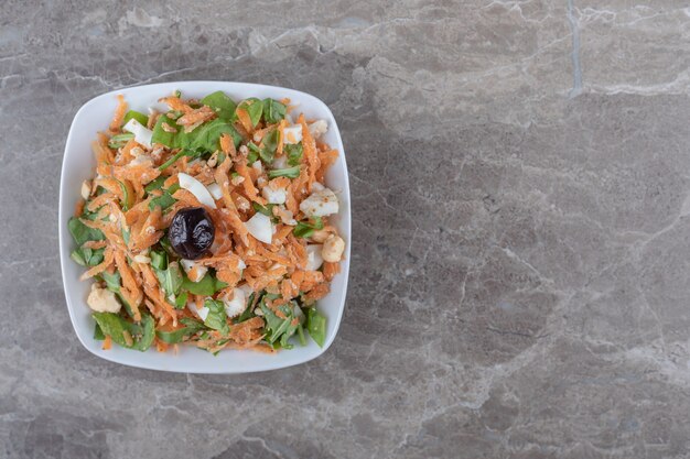 Zanahorias cortadas en cubitos y ensalada de verduras en un tazón blanco.